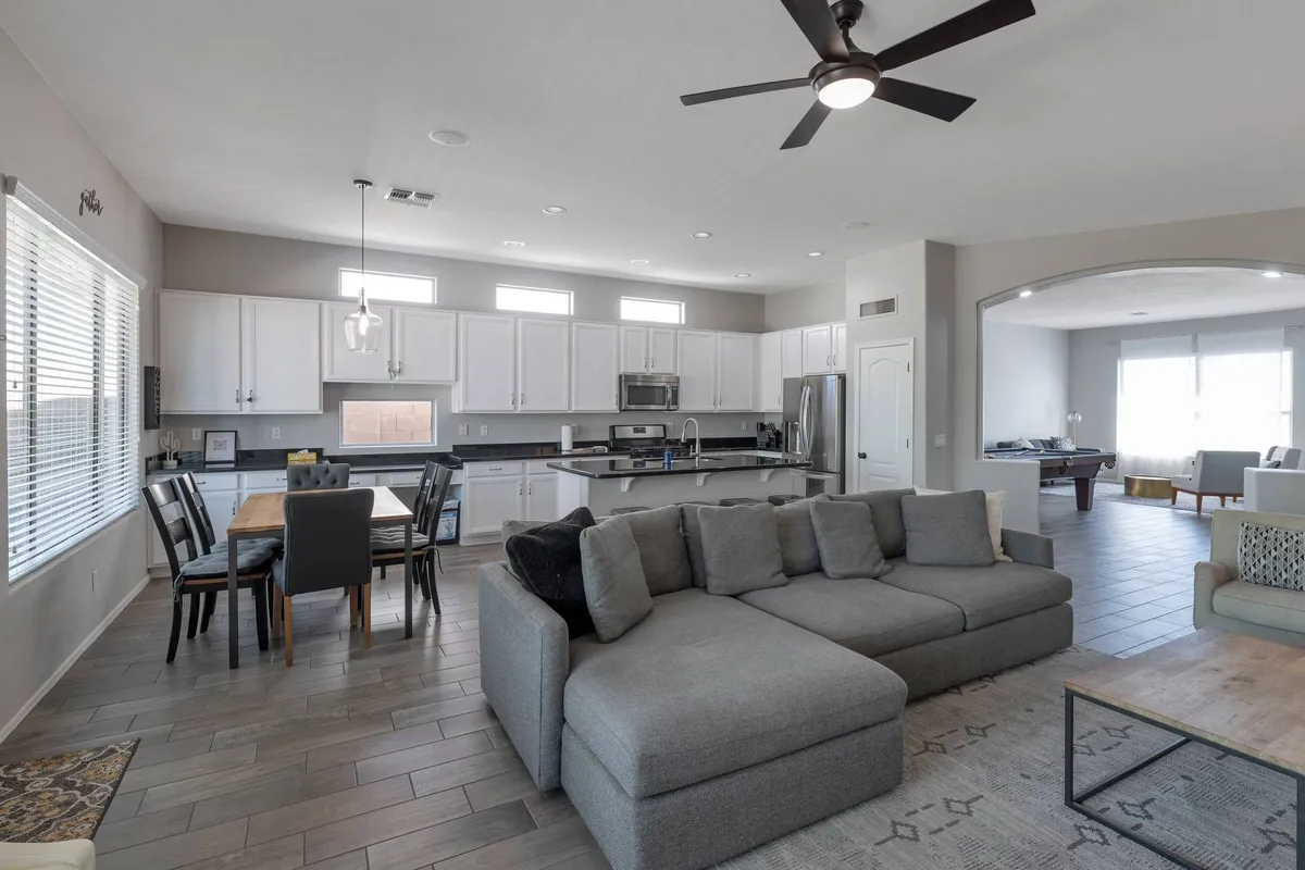 This spacious open-plan living area showcases a large sectional sofa, a dining table, and a kitchen island. The scene exudes comfort and flexibility, ideal for family gatherings or casual entertaining, and emphasizes the seamless flow between lounging, dining, and conversation.